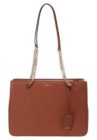 Sac à main en cuir marron avec une forme structurée, deux poignées mettant en valeur un accent en chaîne, et une étiquette de charme décorative. Logo affiché sur le devant.