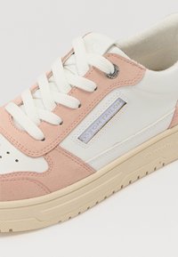 Baskets avec une tige en cuir blanc et en daim rose, bout rond, fermeture à lacets sur le devant, et étiquette de logo. Semelle plateforme avec un motif en caoutchouc texturé.