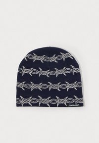 Tengerészkék kötött sapka vízszintes világosszürke kerítéssor mintával és kis "Santa Cruz" címkével az alsó szélen.