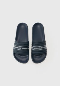 Námornícke modré šľapky s textúrovaným povrchom a tromi horizontálnymi pruhmi zdobenými opakujúcim sa bielym logom. Hladký dizajn podrážky.