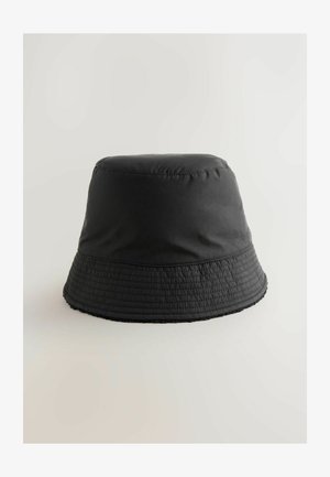 Melnas bucket cepures izgatavotas no viegla, teksturēta auduma. Tai ir plata, šūnāma malas un gluda augšējā daļa.