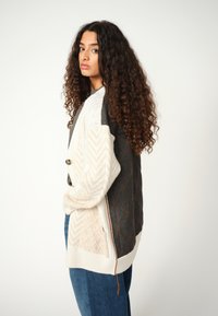 Strickcardigan mit einem Mix aus Creme-, Grau- und Brauntönen; geometrischen Mustern; einer Knopfverschluss und einer strukturierten Optik.