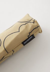 Rouleau de tissu beige avec un motif abstrait noir, comportant une étiquette noire portant le texte "marimekko" à une extrémité. Texture lisse, forme cylindrique.