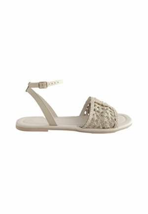 Beige gewebte Sandale mit einem Knöchelriemen, flacher Sohle und einem strukturierten Kreuzbanddesign. Verfügt über ein glattes Lederinnere und dezente Hardwaredetails.