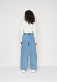 Lys blå denim cargo bukser med bred ben og elastisk talje, der har store sidelommer og en afslappet pasform.