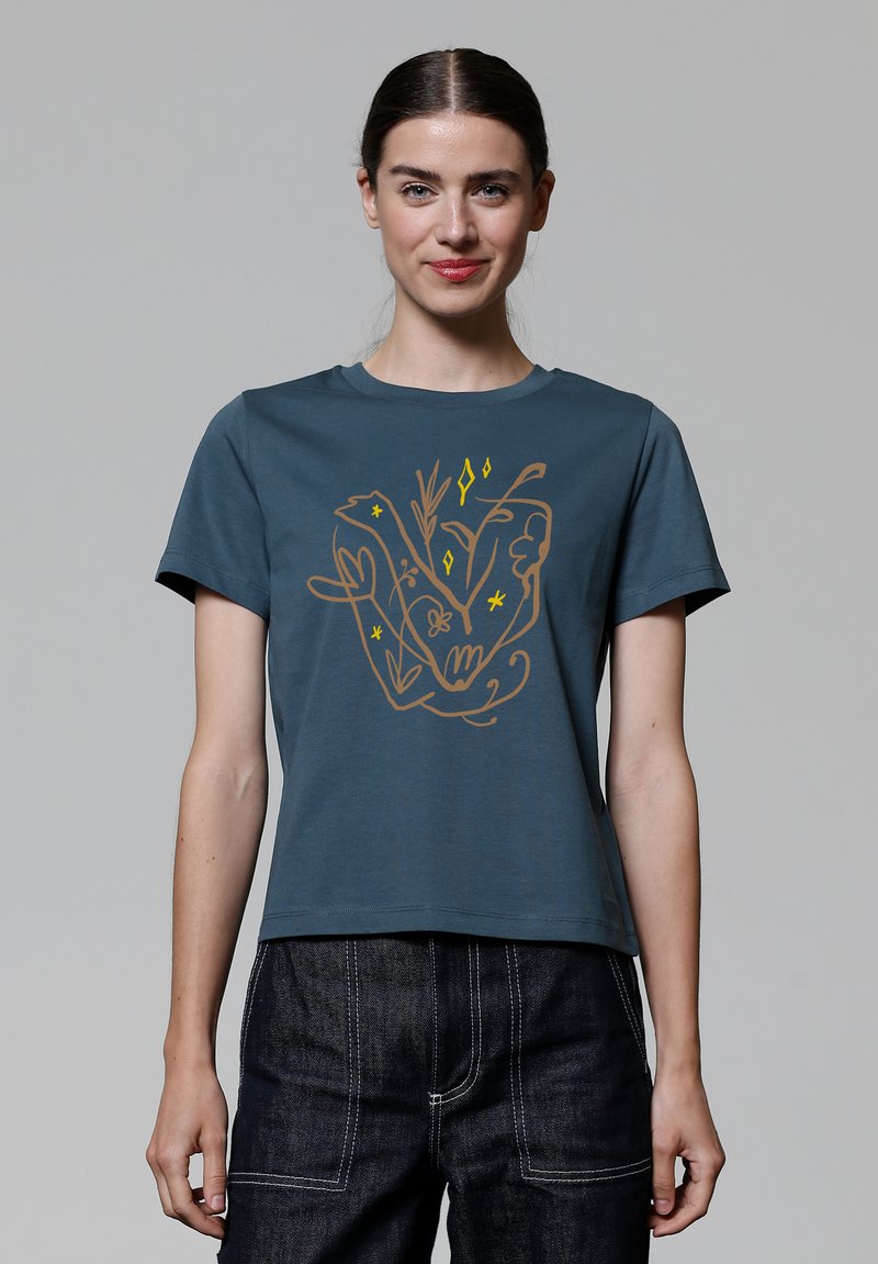 T-shirt en coton bleu canard à manches courtes, avec un motif floral marron et jaune centré sur le devant.