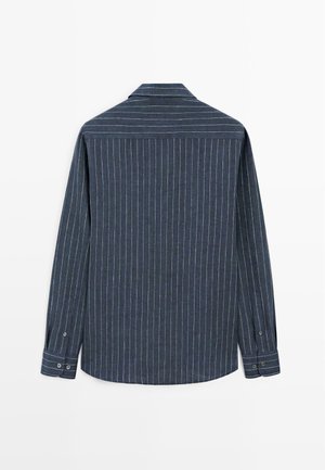 Marineblauw shirt met lange mouwen en dunne witte verticale strepen, met manchetten die zijn vastgeknopt en een puntige kraag, gezien vanaf de achterkant.