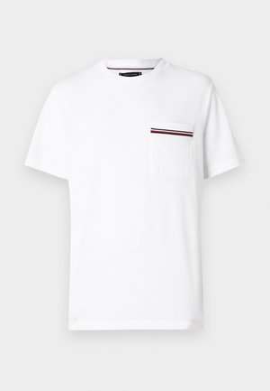 Valge puuvillane t-särk ümar kaelusega ja lühikeste varrukatega. Esiosas tasku, millel punased ja meresinised triibud.