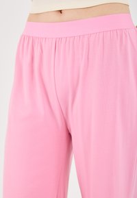 Rosa, lette og elastiske bukser med elastisk midje, med en glatt tekstur og løs passform, passende for hverdagsbruk.