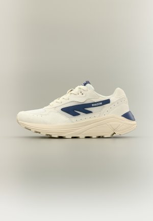 Zapatilla deportiva blanca con acentos en azul marino, parte superior texturizada, cuello acolchado y suela moldeada. Cuenta con un logo y detalles de malla para mayor transpirabilidad.