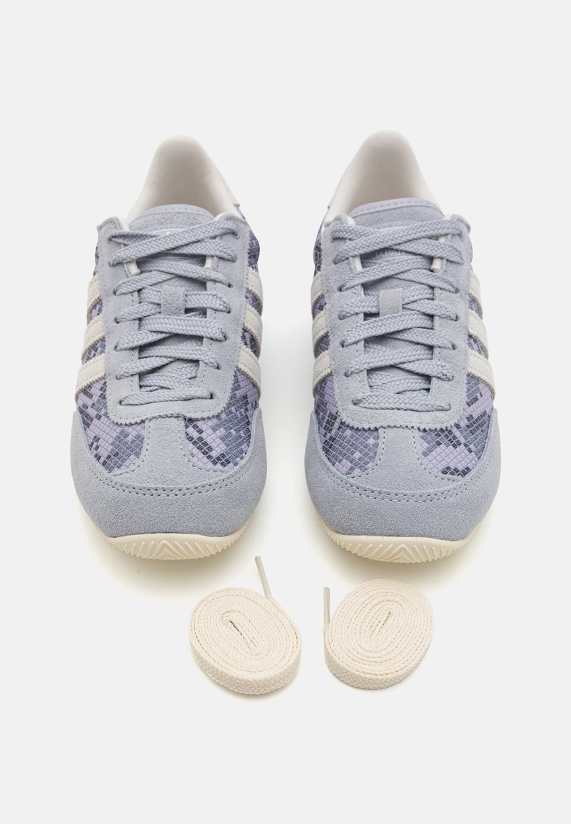 Sneakers in suede blu chiaro con un motivo a serpente viola texture e tre strisce bianche. Include due paia di lacci crema.