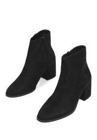 Botas de ante negras hasta el tobillo con punta afilada, tacón cuadrado y cierre lateral con cremallera. Textura suave sin patrones o acentos visibles.