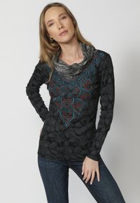 Schwarzes Langarmshirt mit strukturierten Blumenmustern, lebendigen blauen und roten Perlenverzierungen in einem auffälligen Design, ergänzt durch einen grauen Kragen.