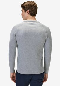Grå ribbad långärmad tröja med rundad halsringning. Baksidan har raglanärmar och en figurnära design, mjuk textur och subtila detaljer.