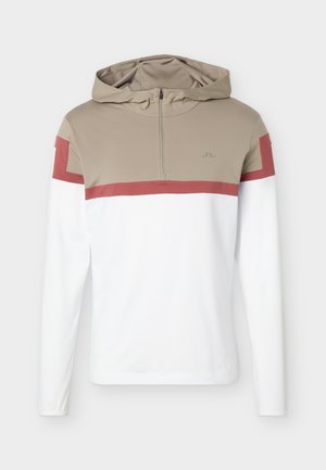 Pull-over à capuche à manches longues avec fermeture éclair frontale, partie supérieure beige, corps inférieur blanc, et bande rougeâtre traversant la poitrine et les manches.