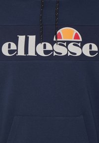 Felpa blu navy con cordini neri, tasca frontale e logo "ellesse" bianco con un emblema semicircolare rosso e arancione.