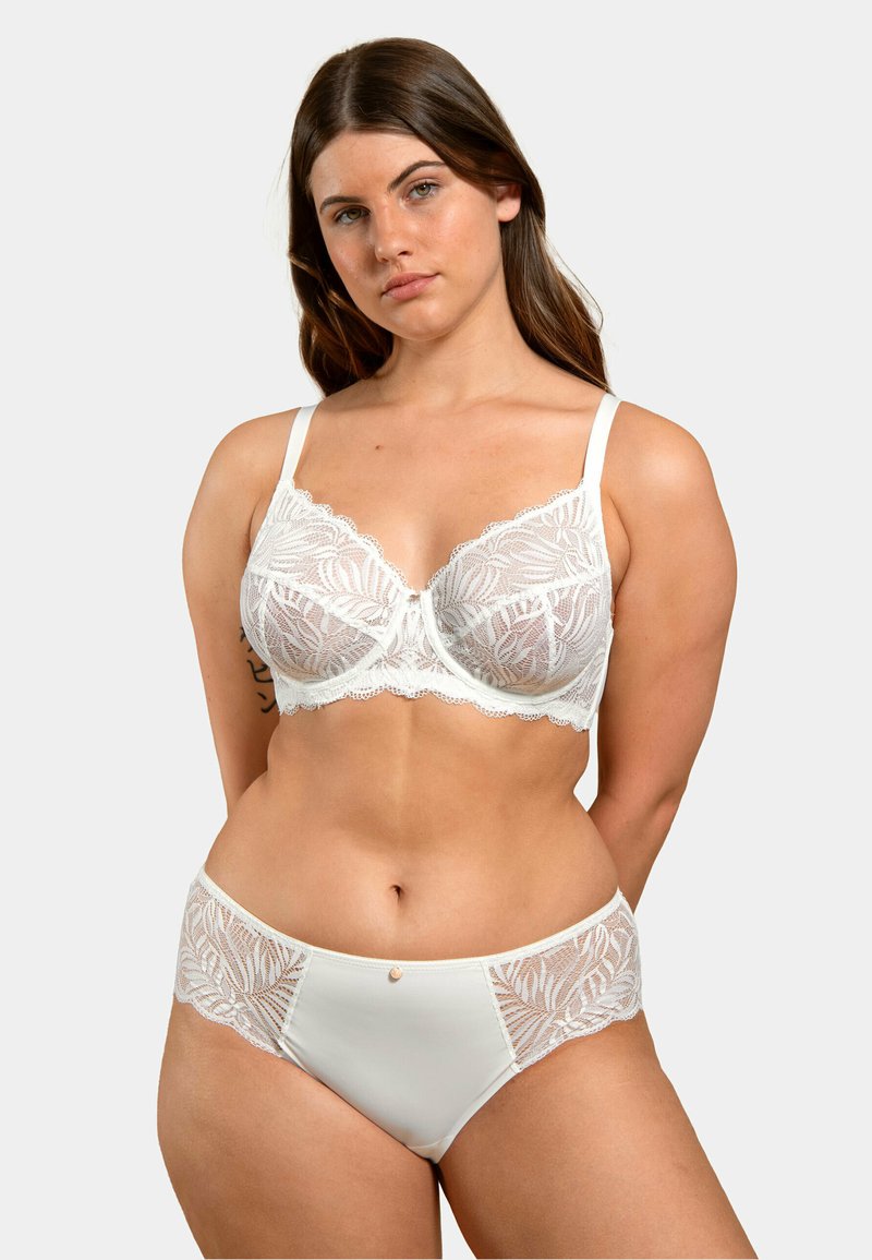 Soutien-gorge en dentelle blanche avec des motifs floraux, support par armatures et bretelles réglables, associé à un slip en dentelle taille haute assorti.