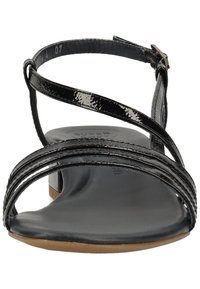 Černé lakované sandály s několika tenkými popruhy, otevřenou špičkou, plochou podrážkou a nastavitelným zapínáním na sponu kolem kotníku.