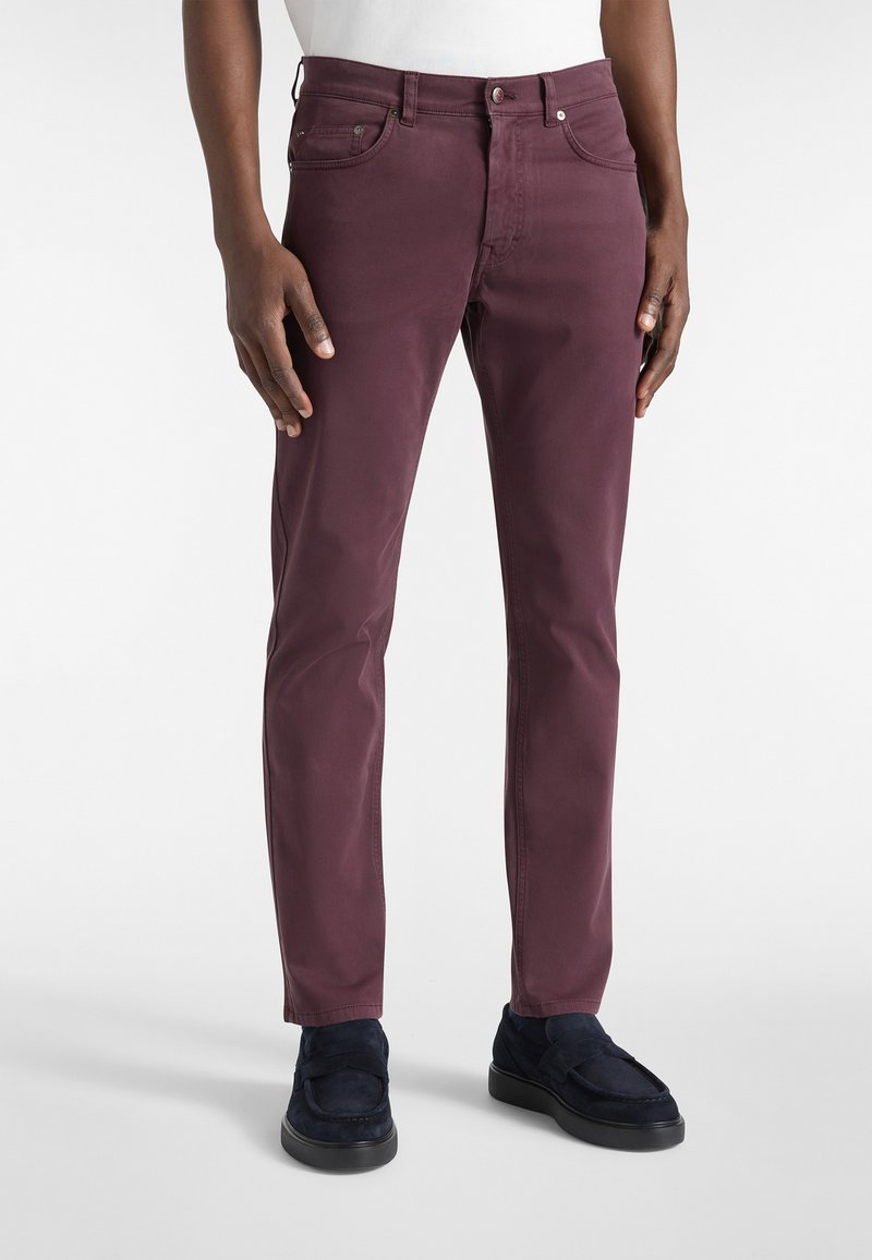 Burgundske slim-fit hlače od glatkog pamuka, s petljama za remen, prednjim dzepovima i zatvaranjem na patentni zatvarač. Uparene s tamnoplave mokasine.