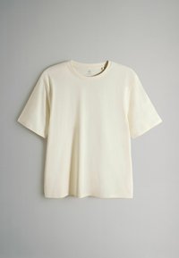 Krämfärgad t-shirt med korta ärmar tillverkad av mjuk bomull, med rund halsringning och enkel, odekorerad design.