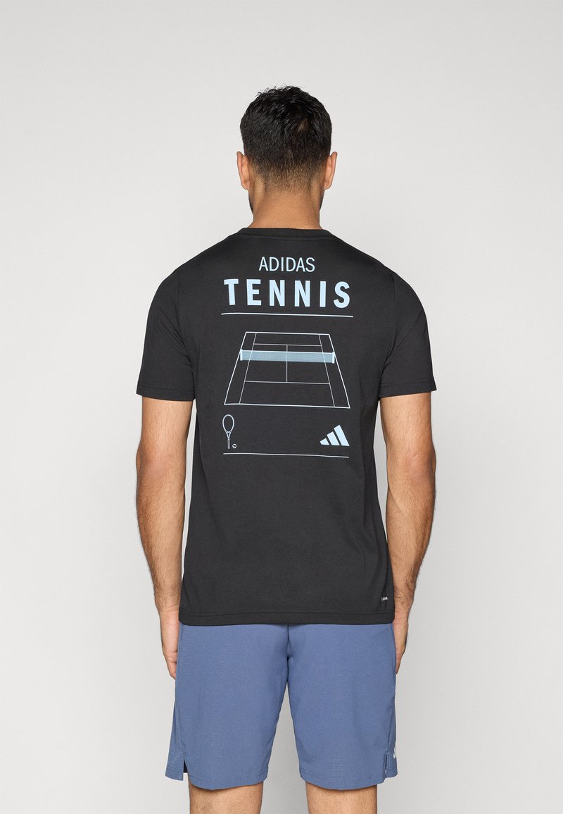 Melnā kokvilnas T-kreklā aizmugurē ir zila grafikā attēlota tenisa korta un raketes zīmējums, virs kura ir uzraksts "ADIDAS TENNIS".