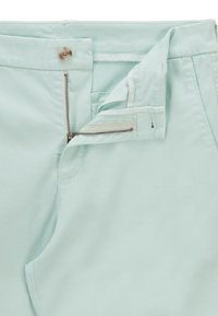 Ljus mynta gröna byxor med dragkedja och knappstängning. Har en slät textur och sömnadsdetaljer längs sömmarna.