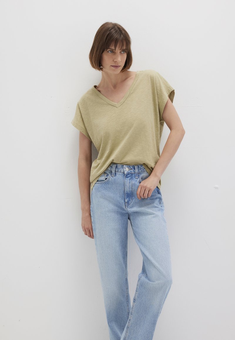 Olive green, short-sleeve V-neck t-shirt paired with light blue high-waisted jeans, both made from soft fabric with a relaxed fit.