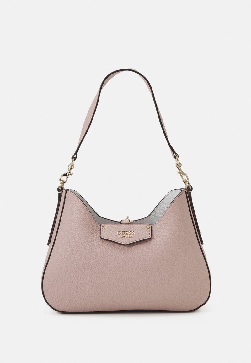 Sac porté épaule en cuir texturé rose clair avec quincaillerie dorée et logo "GUESS EST 1981" sur le rabat avant.