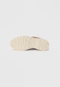 Chaussure en cuir brun avec une tige texturée et une semelle en caoutchouc blanc robuste dotée d'une semelle à motifs pour une meilleure traction.