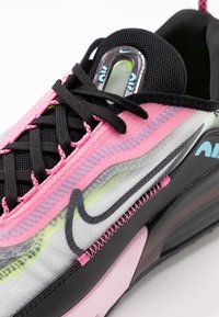 Sneaker Nike caratterizzato da un mix di materiali sintetici rosa e neri, tomaia in rete e accenti traslucidi. Cuciture colorate e unità d'aria visibile.