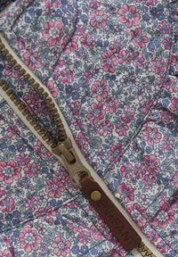 Tissu matelassé avec un motif floral dans des tons de rose et de bleu ; comporte une fermeture éclair dorée avec un tirette en cuir marron et une étiquette de marque.