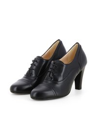 Scarpe in pelle nera con punta affusolata, allacciatura frontale e tacco medio, caratterizzate da cuciture in contrasto lungo i lati.