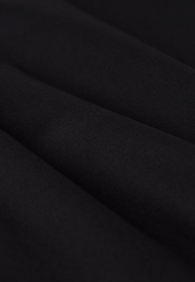 Tessuto nero con una texture liscia, caratterizzato da morbide pieghe drappeggiate. Il materiale appare leggero e uniforme, senza modelli visibili.