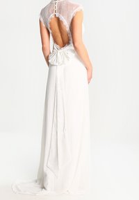 Witte jurk met een kanten kapmouw en een open rug, met een grote satijnen strik op de taille, een vloeiende rok en een gladde textuur.