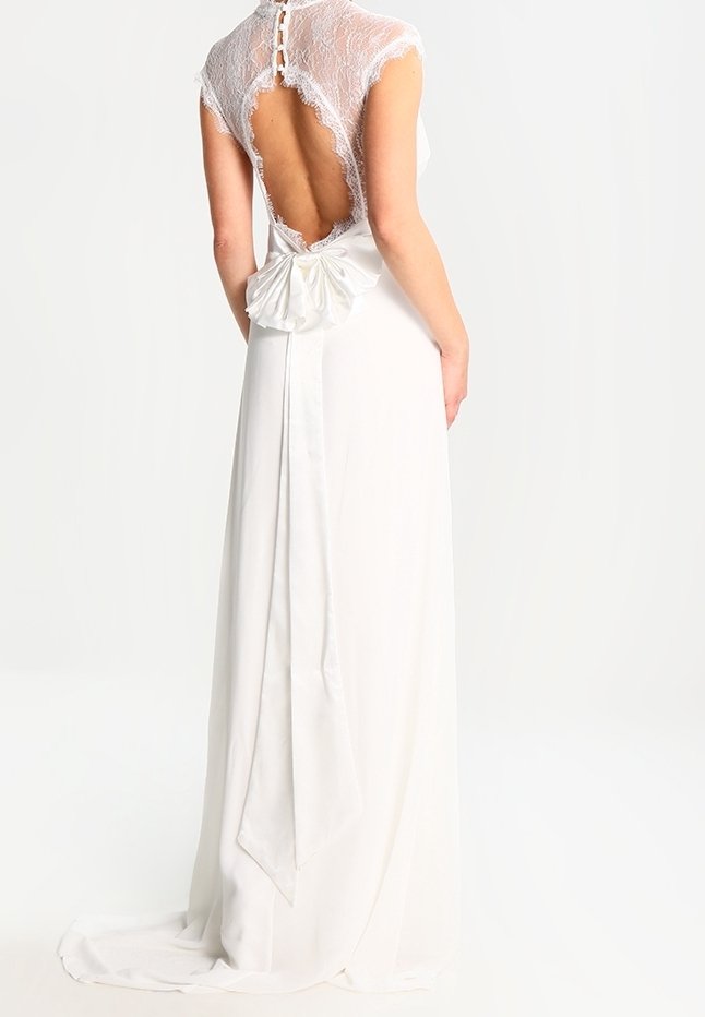 Robe blanche avec des manches en dentelle et un dos nu, ornée d'un grand nœud en satin à la taille, avec une jupe fluide et une texture lisse.
