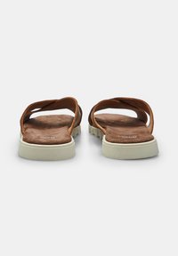 Sandali scivolati in suede marrone con una spessa suola in gomma bianca, caratterizzati da un design open toe e da cinghie curve sul collo del piede.