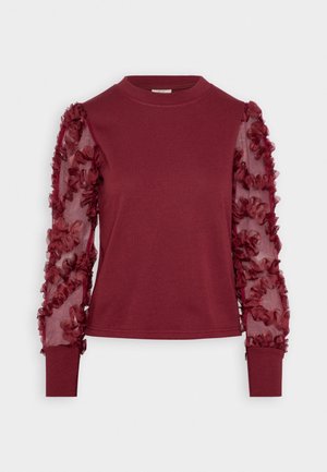 Bordeaux langemouw top met een aansluitend katoenen lichaam en doorzichtige stoffen mouwen versierd met ruffles en bloemdetail. Ronde halslijn en manchetten.
