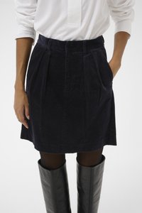 Tengeri kordbársony szoknya pliszírozással, magas derékkal, oldalzsebekkel és térd felett végződő szegéllyel, fekete bőr térdzoknis csizmával párosítva.