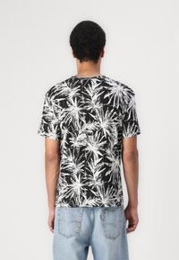 Kortærmet sort t-shirt med mønster af hvide tropiske blade, rund hals og blød tekstur. Bagview med afslappet pasform.