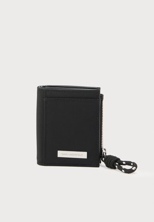 Zwarte nylon portemonnee met ritssluiting, voorzien van een zilverkleurige logoplaat en een gestructureerde geweven band. Compact, rechthoekig ontwerp.