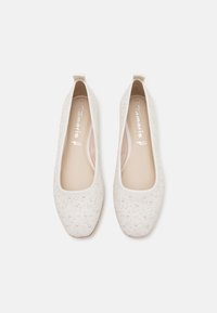 Paire de ballerines blanches texturées avec des bouts carrés arrondis et de petites ornements ressemblant à des perles, portant l'étiquette Tamaris à l'intérieur.