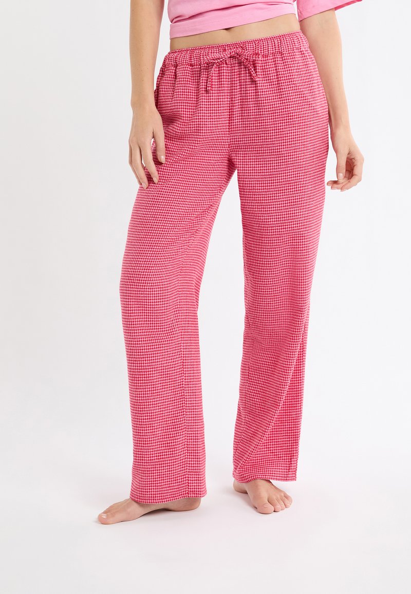 Różowe spodnie piżamowe w kratkę z sznurkiem w pasie, cechujące się luźnym krojem i lekką tkaniną. Wzór zawiera drobną kratkę.