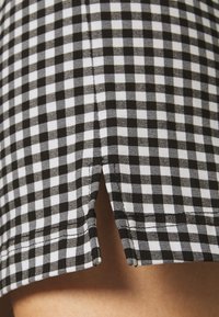 Randigt tyg i svart och vitt med en delad nederkant och synliga sömmar, samt en slät textur.