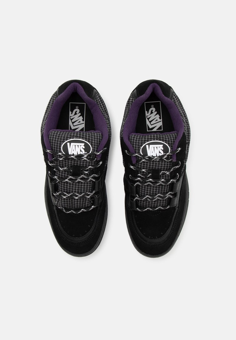 Schwarze und graue Sneaker mit einem strukturierten karierten Muster. Mit Wildlederakzenten, schwarzen Schnürsenkeln und einem gepolsterten Kragen in lila. Vans-Logo sichtbar.