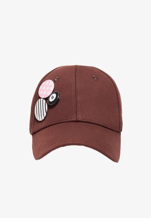 Braune Baseballkappe mit drei dekorativen Pins: pink-kariert im Hahnentrittmuster, schwarz-weiß gestreift und ein schwarzes 8-Ball-Design.