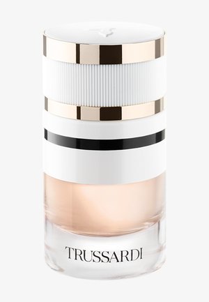 Flacon de parfum cylindrique transparent avec liquide couleur pêche claire, bouchon blanc et or, et « TRUSSARDI » imprimé à la base.