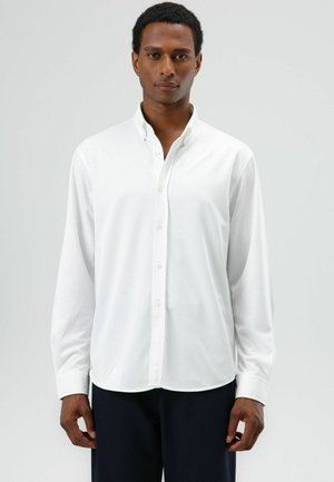 Wit shirt met lange mouwen en een knoopsluiting bij de kraag, gladde textuur en rechte zoom. Voorzien van een voorpand met knopen in dezelfde kleur.