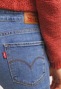Levi's blaue Denim-Jeans mit einem hellbraunen Lederpatch, rotem Tab und charakteristischer, geschwungener Naht auf den Gesäßtaschen.