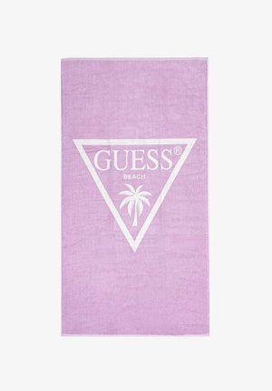 Asciugamano da spiaggia lavanda con logo a triangolo bianco che presenta le parole "GUESS", "BEACH" e una palma all'interno del triangolo.