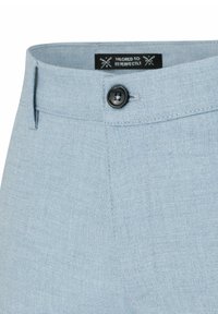 Jasnoniebieskie spodnie o dopasowanym kroju z fakturowanym wykończeniem, z czarnym guzikiem i metką wewnątrz, podkreślające czysty design pasa.